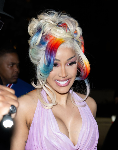Cardi B smiliing with a blonde and rainbow updo